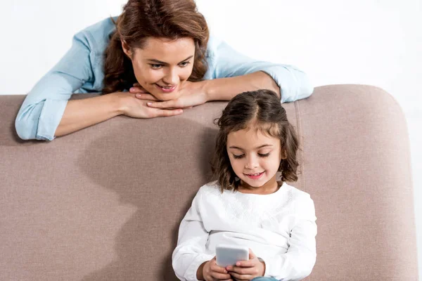 Smiling Mother Looking How Daugher Using Smartphone While Sitting Sofa — Stock Photo, Image