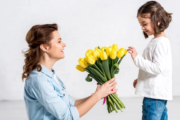 Кучерява Усміхнена Мати Дочка Дивляться Букет Жовтих Тюльпанів Білому — стокове фото