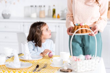 Paskalya kek ile kadın ve çocuk mutfakta boyalı yumurta ile görünümünü kırpılmış
