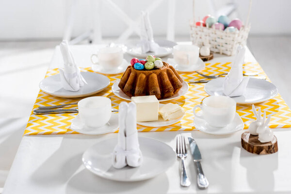 Easter cake, painted eggs and crockery on table in kitchen