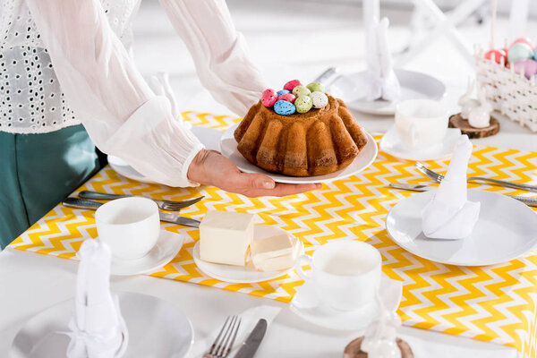 Partial view of woman in white blouse serving table for easter 