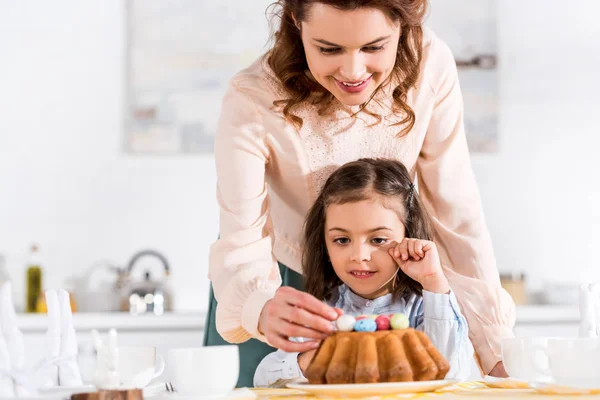 Madre Sonriente Hija Pequeña Decorando Pastel Pascua Con Huevos Pintados — Foto de Stock