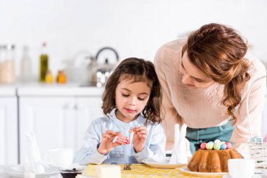 Neşeli kadın mutfakta acıbadem kurabiyesi yeme kızı bakarak