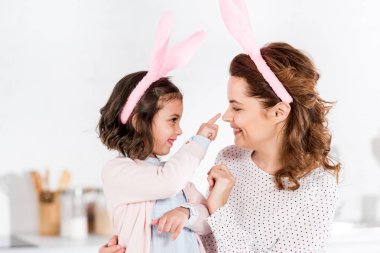 Mother and daughter in bunny ears playing and looking at each other clipart