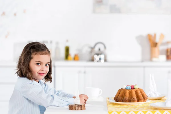 Anak Tersenyum Duduk Meja Dengan Kue Paskah Dan Melihat Kamera — Stok Foto