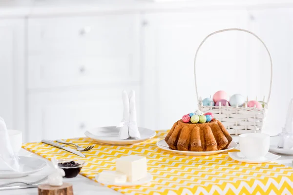 黄色のテーブル クロスに塗られた卵をイースター ケーキおよび枝編み細工品バスケット — ストック写真