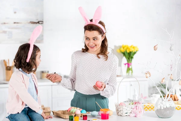 Smiling Woman Bunny Ears Looking Daughter While Painting Easter Egg — Stock Photo, Image