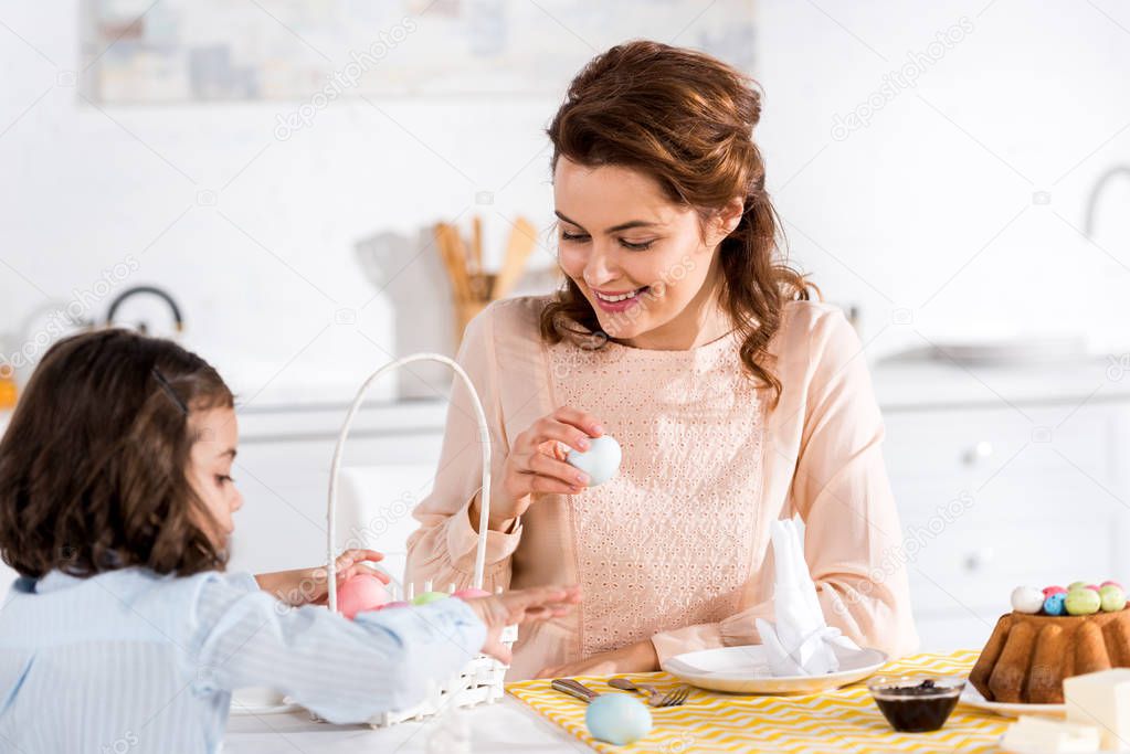Mother and child sitting at table with painted easter eggs in kitchen