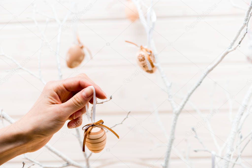 Cropped view of woman decorating easter tree with eggs 