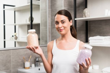 Cam Kavanoz deniz tuzu ile banyoda tutan neşeli esmer kadın 