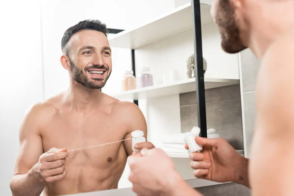 Happy Bearded Man Holding Dental Floss While Looking Mirror Bathroom — Stock Photo, Image