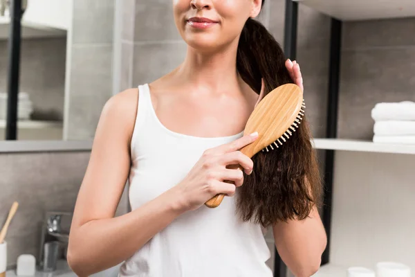 Recortado Vista Sonriente Morena Mujer Cepillando Pelo Mientras Está Pie — Foto de Stock