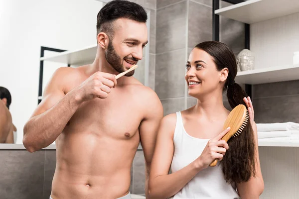 Bonito Shirtless Homem Olhando Para Atraente Namorada Escovando Cabelo Banheiro — Fotografia de Stock