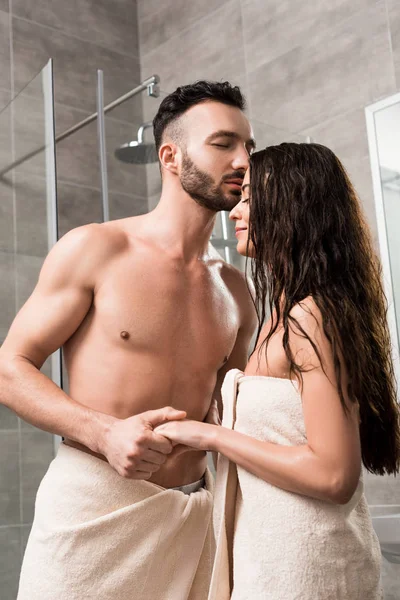 英俊的胡须男子亲吻快乐的黑发女人 并在浴室牵手 — 图库照片