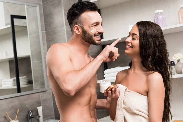 开朗的无袖男友应用在黑发女友的鼻子上的面霜 — 图库照片