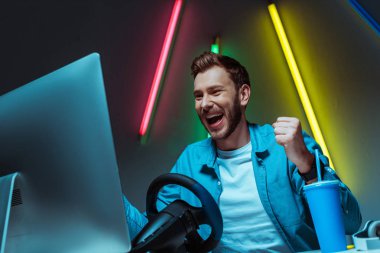 yakışıklı ve gülümseyen adam direksiyon ile video oyunu oynuyor