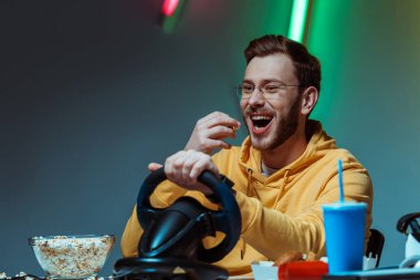 gözlük ve güzel görünümlü adam direksiyon ile oynarken ve Popcorn yeme gülümseyen 
