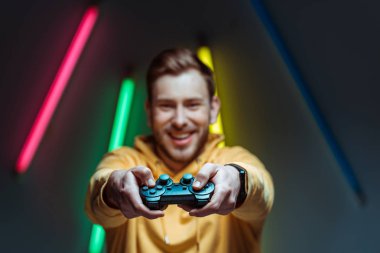 yakışıklı ve gülümseyen adamın seçici odak gamepad tutarak 