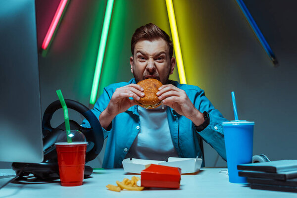 handsome and good-looking man eating burger and looking at camera 