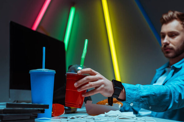 selective focus of handsome man holding plastic cup with drink 