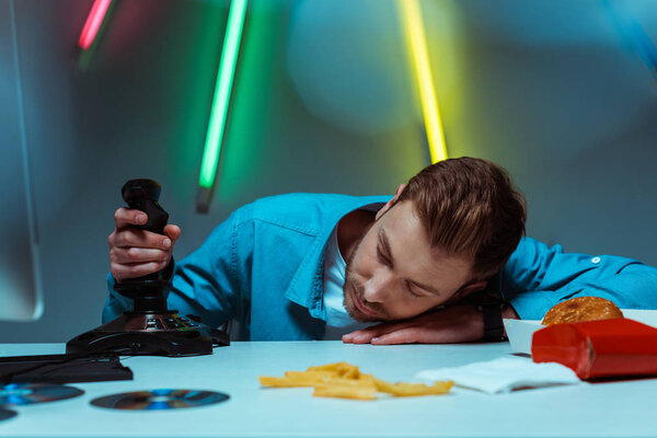 handsome young adult man sleeping on table and holding joystick 