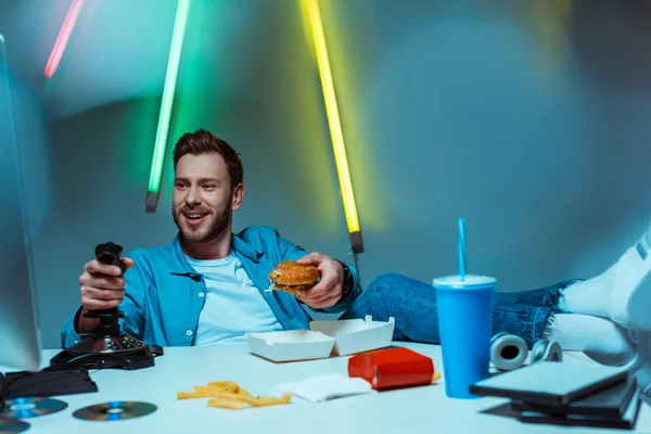Handsome Cyber Sportsman Playing Video Game Joystick Holding Burger — Stock Photo, Image