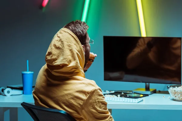 Back View Van Mens Eten Smakelijke Hamburger Kijken Naar Computerscherm — Stockfoto