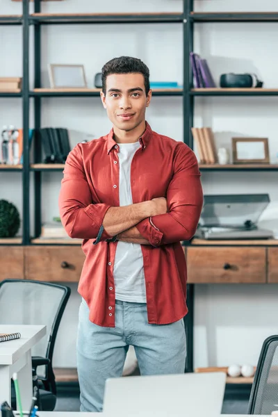 Joyful Young Man Red Shirt Standing Crossed Arms Workplace — Stock Photo, Image