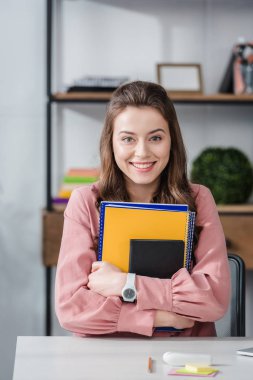 Pembe gömlek çekici öğrenci gülümseme ile Notebook tutarak