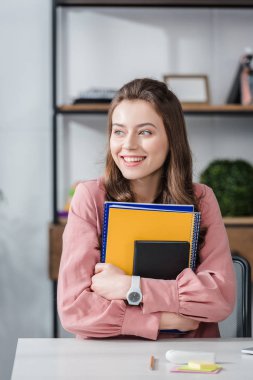 Pembe gömlek çekici öğrenci gülümseme ile Notebook tutarak