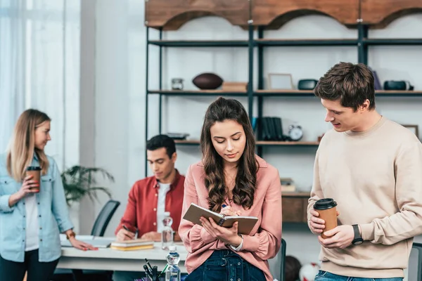 Ung Man Med Kopp Kaffe Tittar Flickan Skriver Antecknings Boken — Stockfoto