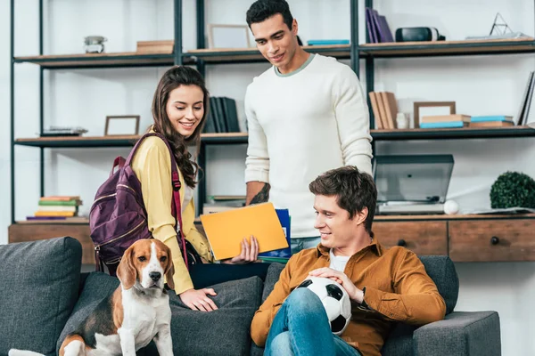 Tři Multikulturní Studenti Notebookem Fotbalovým Míčkem Kteří Sedí Pohovce Psem — Stock fotografie