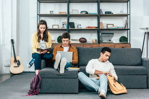 Три Мультикультурні Студенти Блокнотами Ноутбуком Які Навчаються Сидячи Дивані — стокове фото