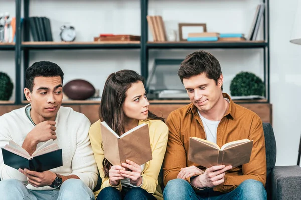 Tres Estudiantes Multiculturales Sentados Sofá Leyendo Libros Salón — Foto de Stock