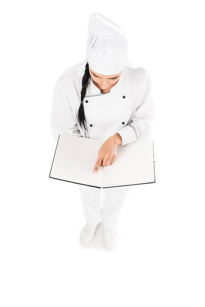 Brunette chef in uniform reading book isolated on white