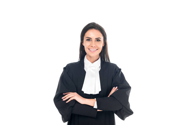 Front view of smiling judge in judicial robe standing with folded arms isolated on white