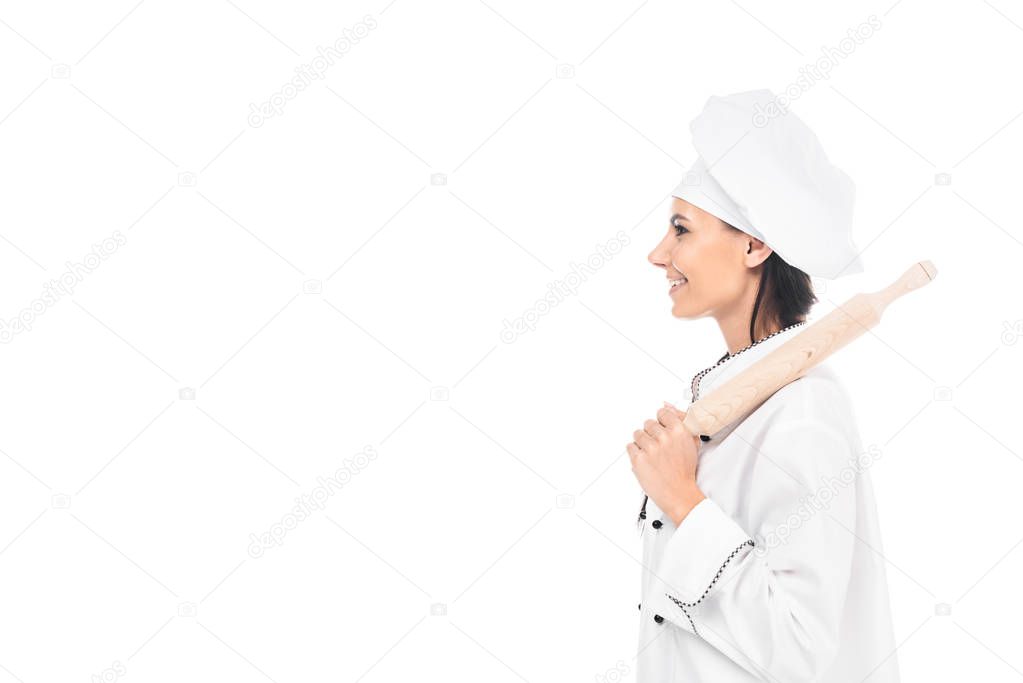 Side view of chef in hat holding rolling pin isolated on white