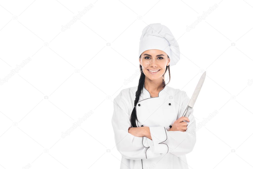 Smiling chef in uniform holding knife with crossed arms isolated on white