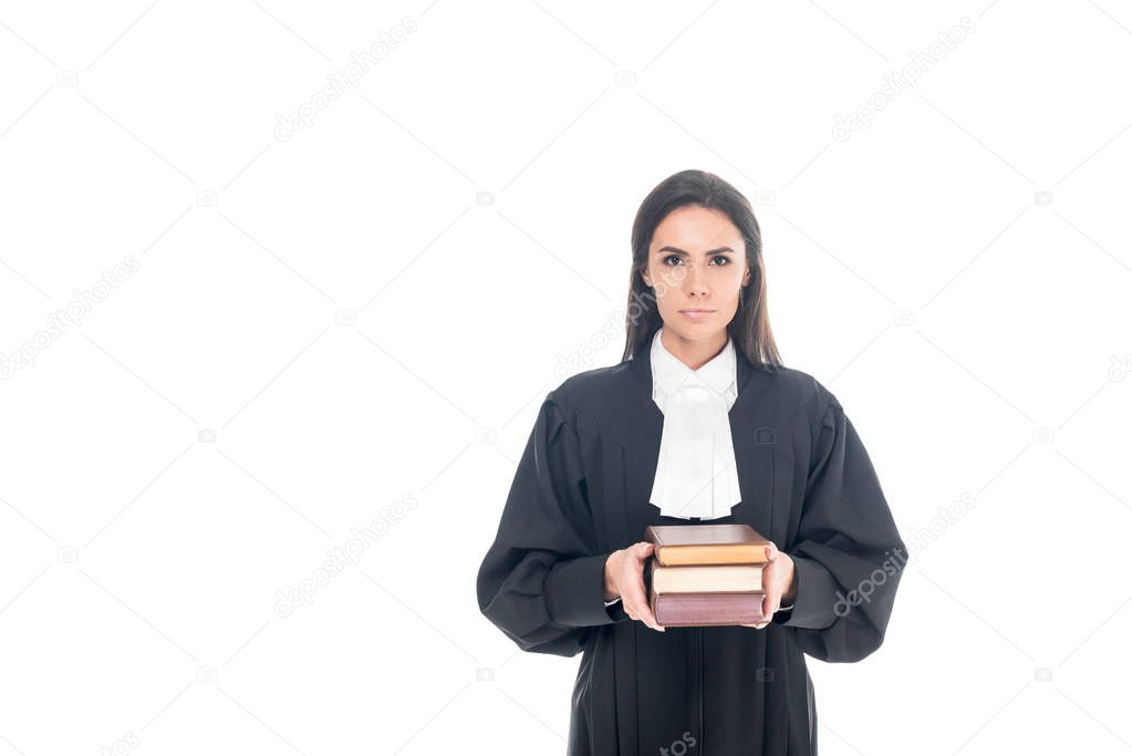 Serious judge in judicial robe holding books isolated on white