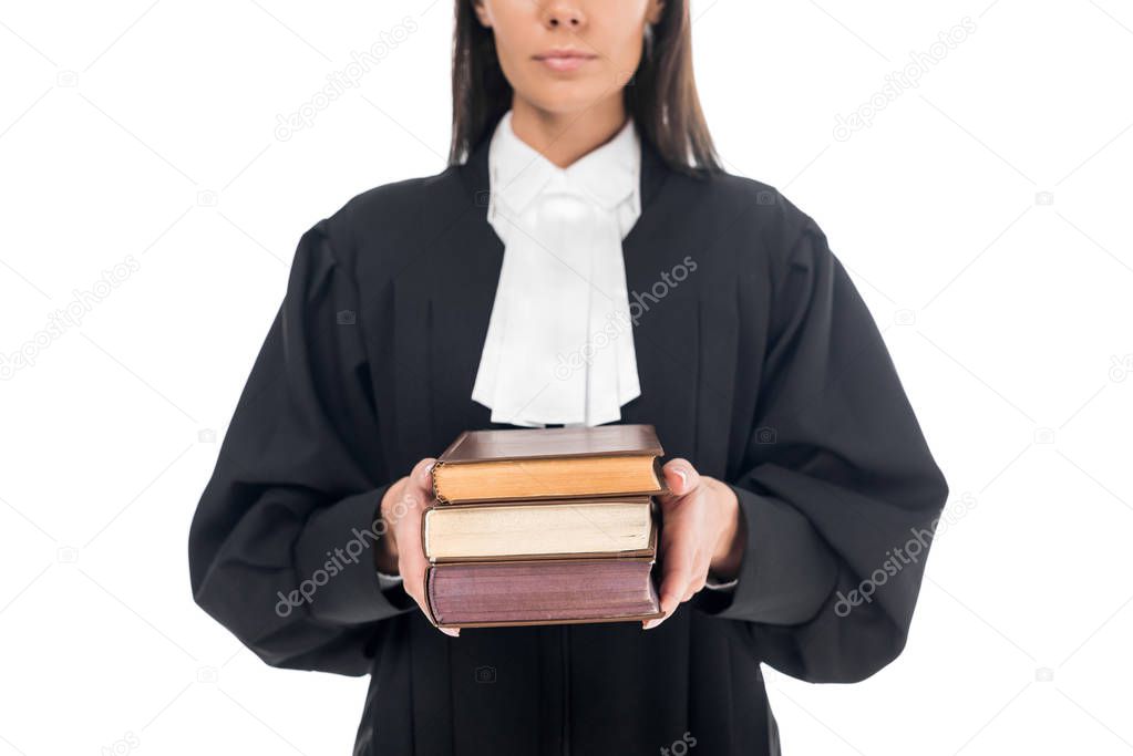 Cropped view of serious judge in judicial robe holding books isolated on white