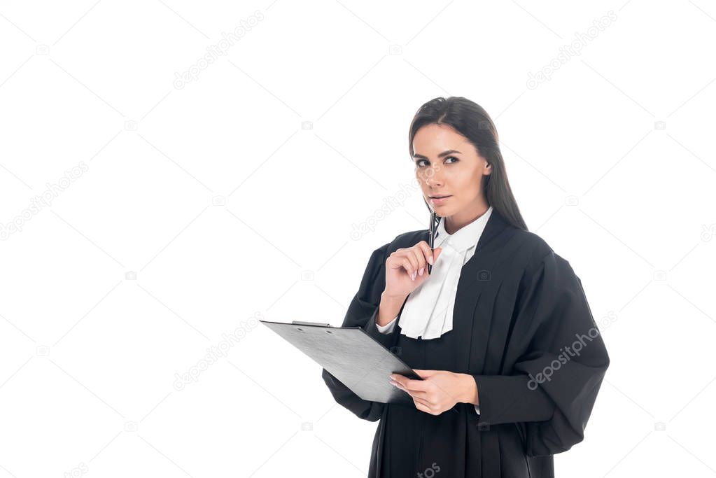 Pensive judge in judicial robe holding clipboard and pen isolated on white