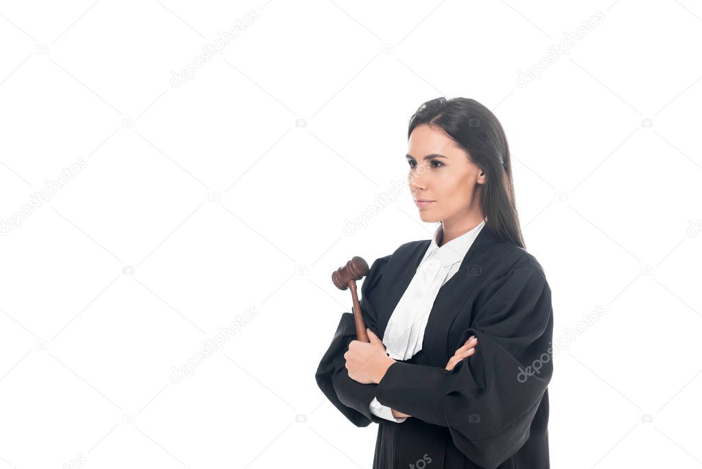 Judge in judicial robe holding gavel and standing with folded arms isolated on white