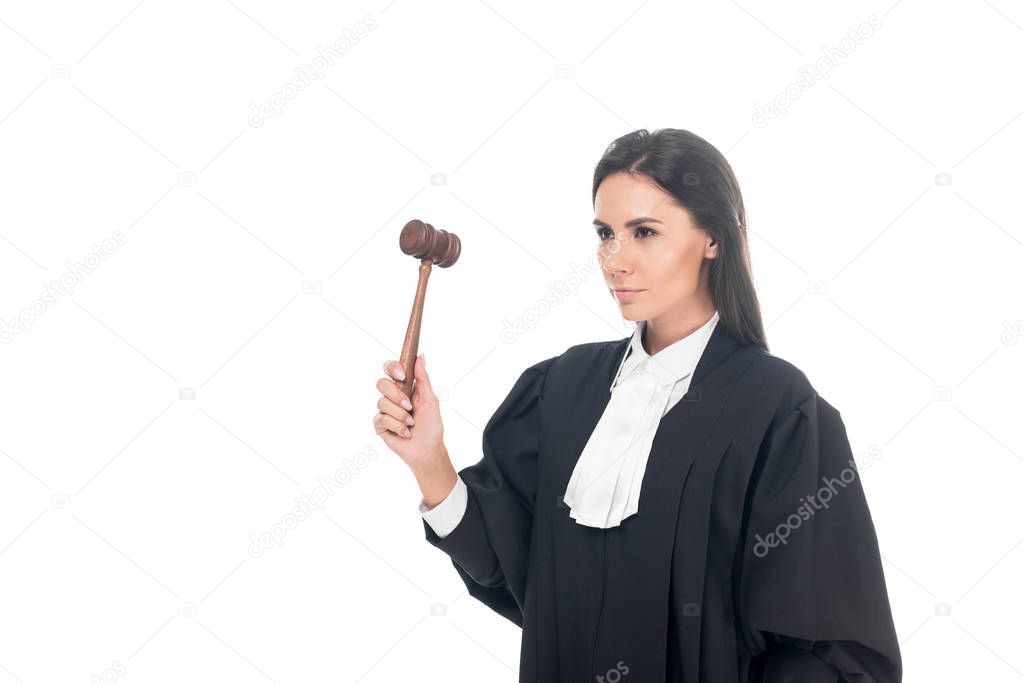 Serious brunette judge in judicial robe holding gavel isolated on white