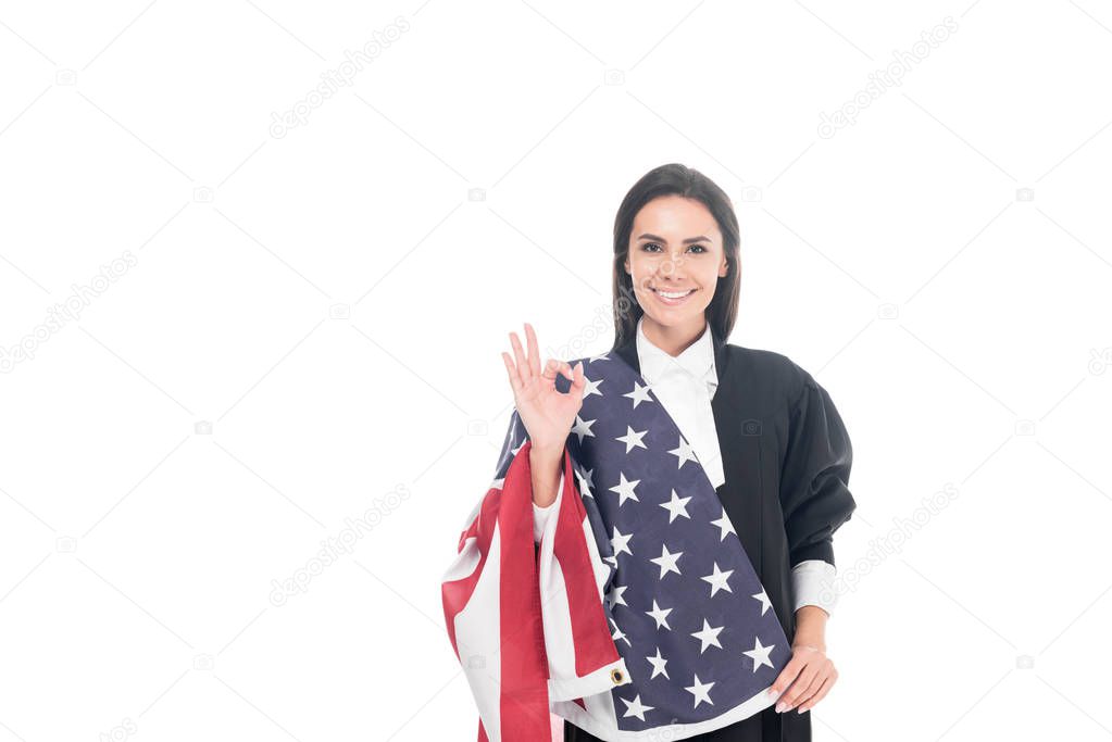 Smiling judge holding american flag and showing okay sign isolated on white