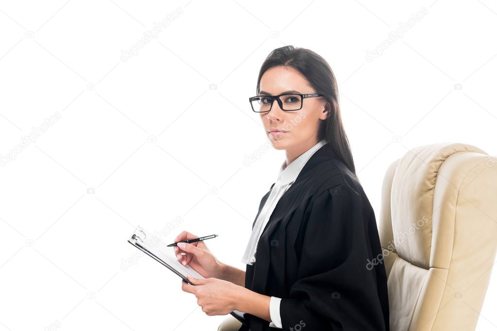 Judge sitting in armchair and writing on clipboard isolated on white