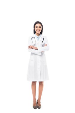 Beyaz önlük ayakta beyaz izole katlanmış silah ile neşeli doktor görünümünü tam uzunlukta