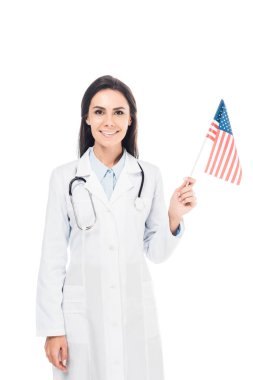 Amerikan bayrağı üzerinde beyaz izole elinde stetoskop ile gülümseyen doktor