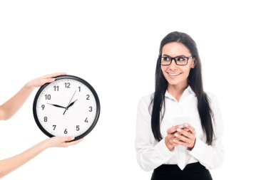 Smiling businesswoman in glasses standing near clock isolated on white clipart