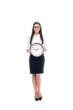 Full length view of elegant brunette businesswoman in shirt holding clock isolated on white clipart