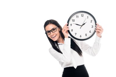 Smiling brunette businesswoman in shirt holding clock isolated on white clipart